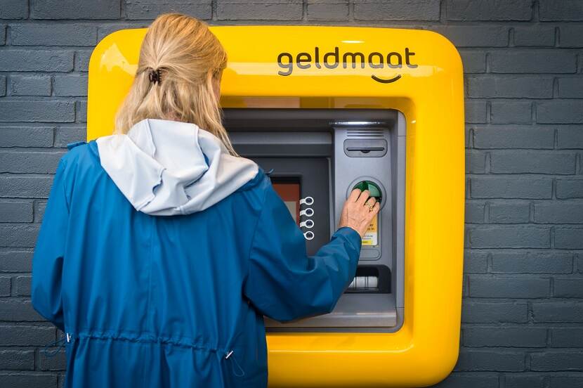 Iemand pint geld bij een geldautomaat die voorzien is van spraakondersteuning