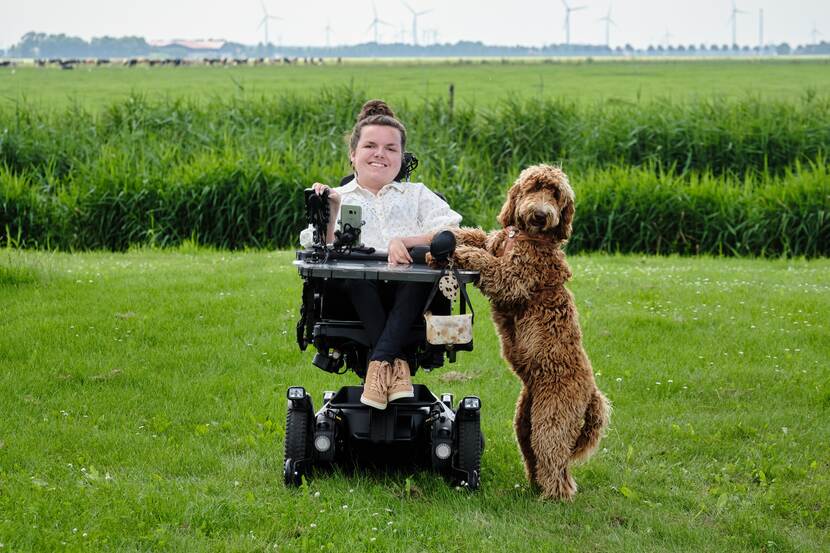 Een vrouw in een rolstoel met een hond op een grasveld